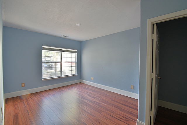 empty room with hardwood / wood-style floors and a textured ceiling