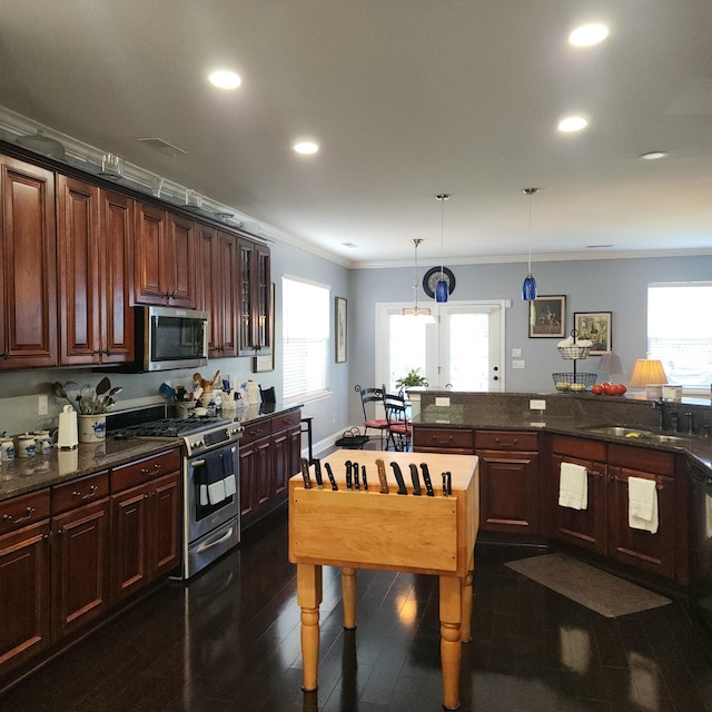 kitchen featuring appliances with stainless steel finishes, ornamental molding, a sink, hanging light fixtures, and recessed lighting