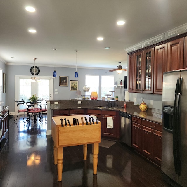 kitchen with appliances with stainless steel finishes, a peninsula, ornamental molding, a sink, and recessed lighting