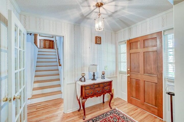 foyer featuring ornamental molding, hardwood / wood-style floors, a textured ceiling, and plenty of natural light