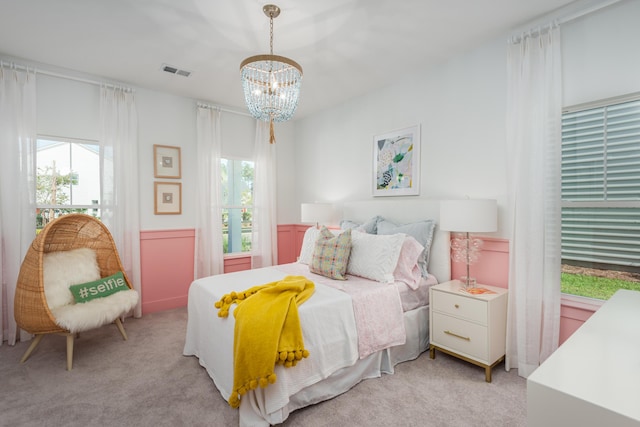 bedroom featuring light carpet and an inviting chandelier