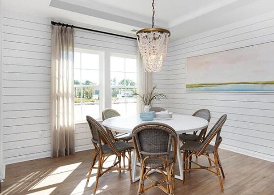 dining room featuring a tray ceiling, an inviting chandelier, and dark wood-type flooring