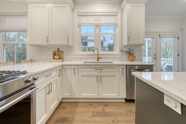 kitchen featuring a sink, ornamental molding, stainless steel appliances, and white cabinets