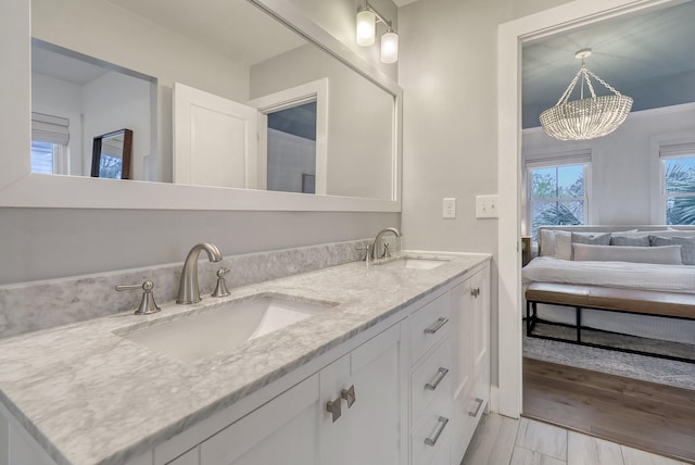 full bath with a sink, double vanity, and a notable chandelier