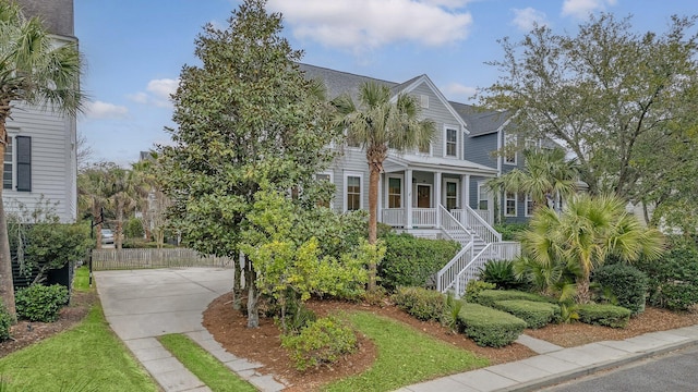 view of front facade with concrete driveway, a porch, fence, and stairs