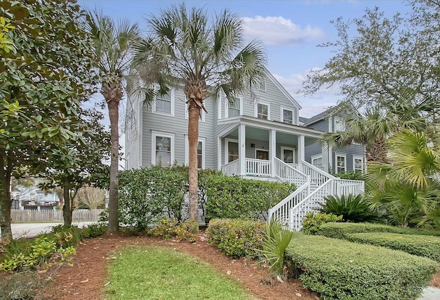 view of front of property with a porch, stairway, and fence