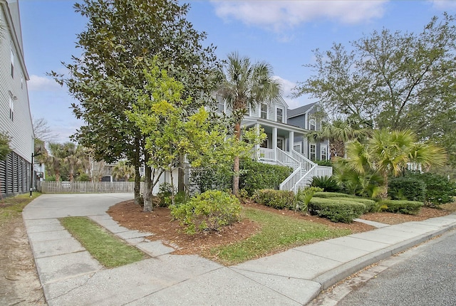 view of home's exterior with a porch, stairway, and fence