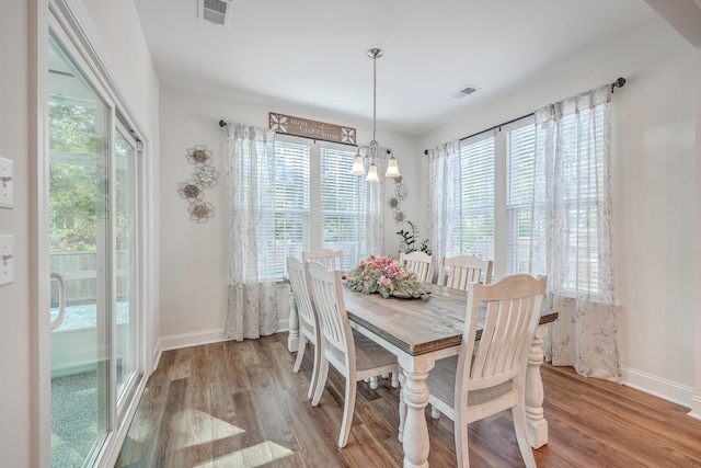 dining area with a chandelier, wood finished floors, and baseboards