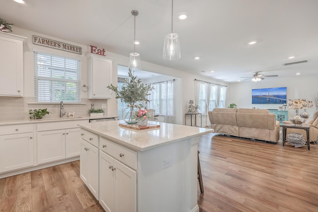 kitchen featuring plenty of natural light, light wood finished floors, open floor plan, a sink, and recessed lighting