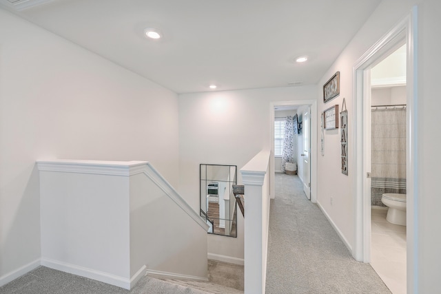 corridor with an upstairs landing, light colored carpet, recessed lighting, baseboards, and light tile patterned flooring