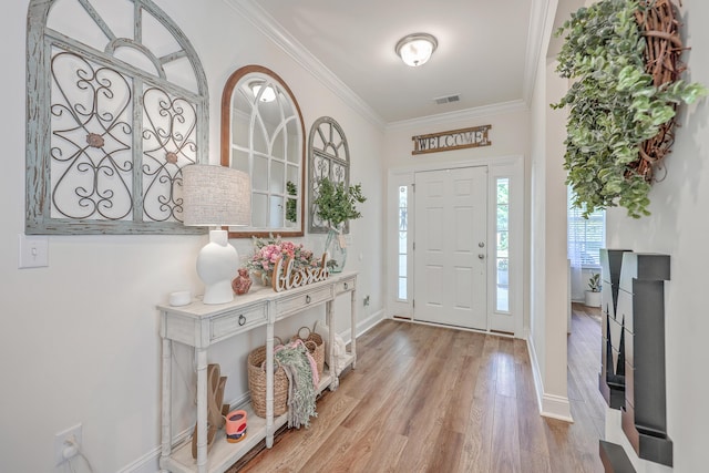 entryway with wood finished floors, ornamental molding, plenty of natural light, and baseboards