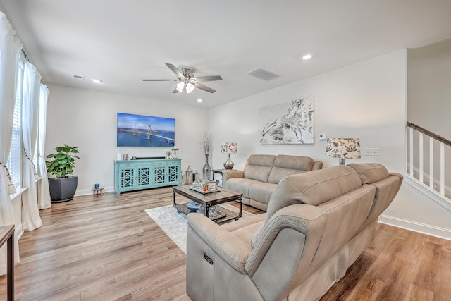 living room with light wood-style flooring, ceiling fan, recessed lighting, baseboards, and stairway