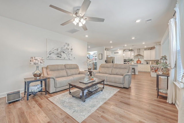 living room with a ceiling fan, light wood-style floors, and recessed lighting
