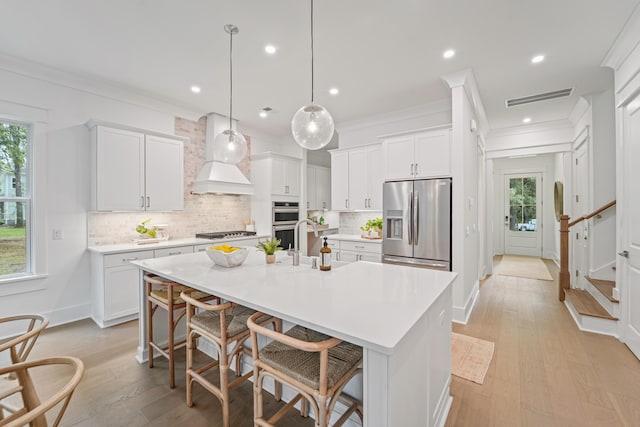 5710 Barbary Coast Rd, Hollywood, SC 29449 - kitchen with stainless steel appliances, custom exhaust hood, light countertops, a center island with sink, and backsplash