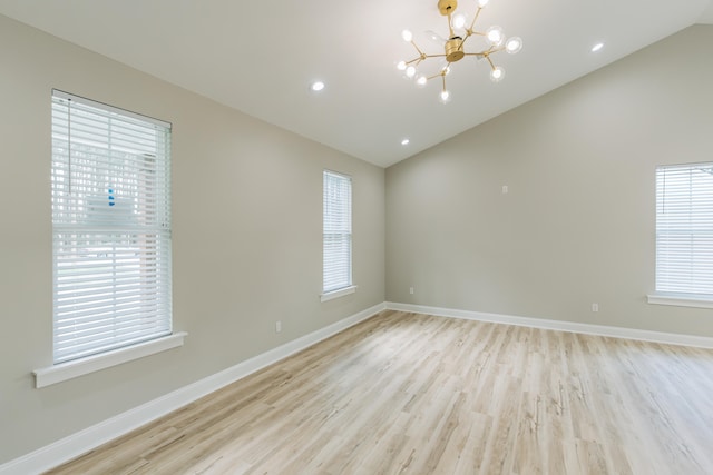 spare room featuring light wood-style floors, plenty of natural light, and lofted ceiling