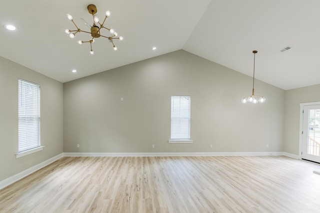 empty room with an inviting chandelier, light wood finished floors, baseboards, and vaulted ceiling