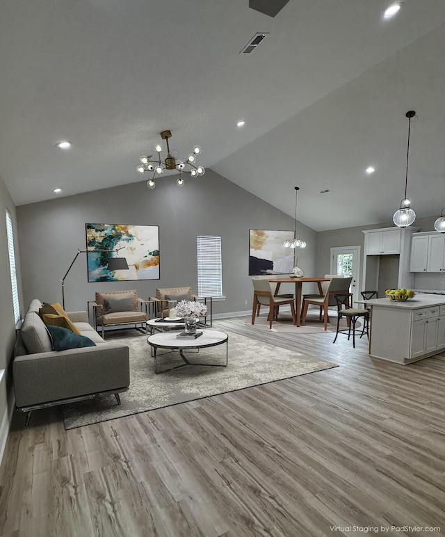 living room with visible vents, vaulted ceiling, baseboards, light wood finished floors, and a notable chandelier