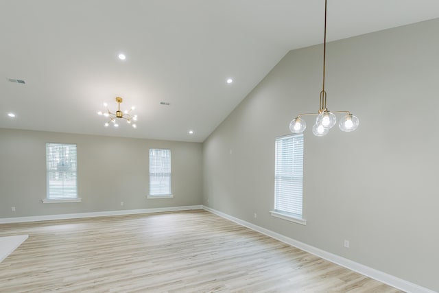 empty room with vaulted ceiling, a notable chandelier, a healthy amount of sunlight, and visible vents