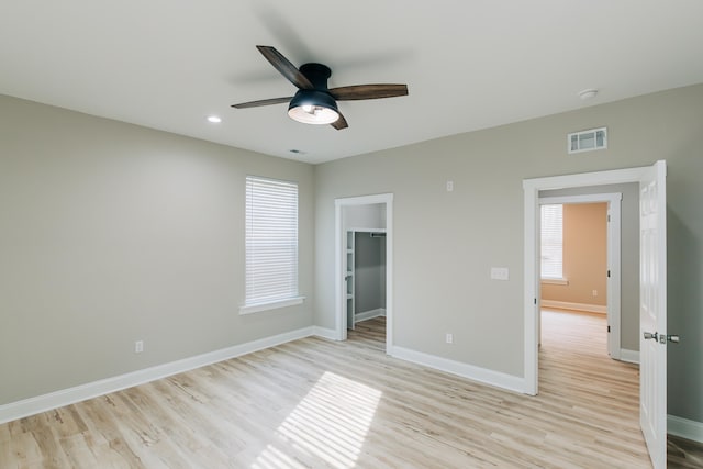 unfurnished bedroom with a walk in closet, visible vents, baseboards, recessed lighting, and light wood-style flooring