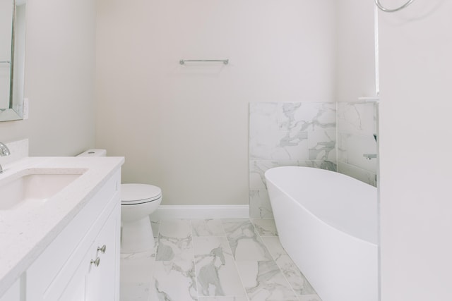 bathroom with vanity, marble finish floor, toilet, and a soaking tub