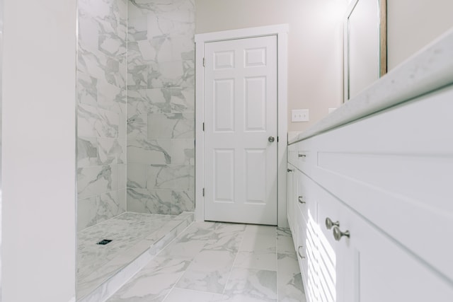 full bathroom with vanity, a tile shower, and marble finish floor