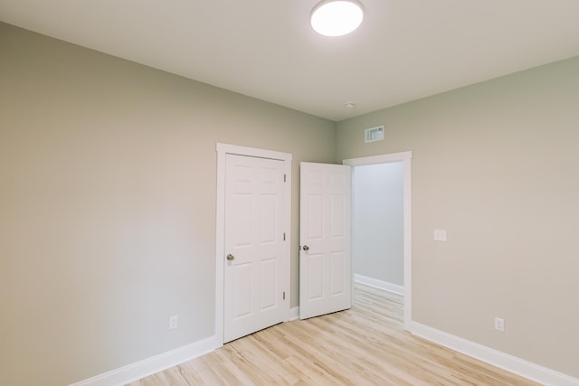unfurnished room featuring baseboards, visible vents, and light wood-type flooring