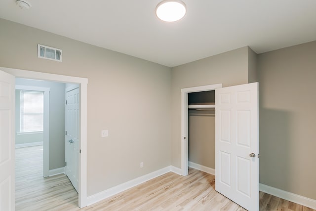 unfurnished bedroom featuring baseboards, a closet, light wood-type flooring, and visible vents