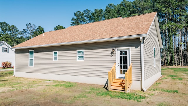 rear view of house featuring entry steps and a shingled roof