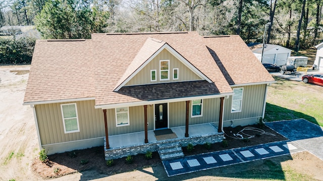 view of front of house with board and batten siding, a shingled roof, and a porch