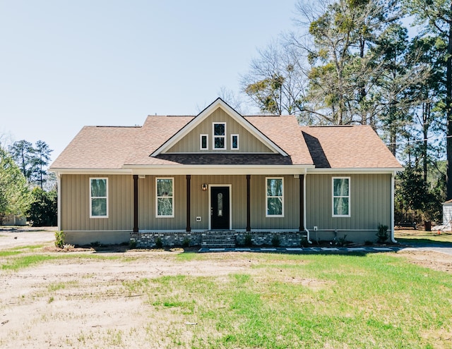 view of front facade with a porch, roof with shingles, and a front lawn