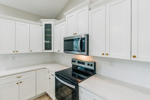 kitchen featuring electric range oven, stainless steel microwave, white cabinets, and tasteful backsplash
