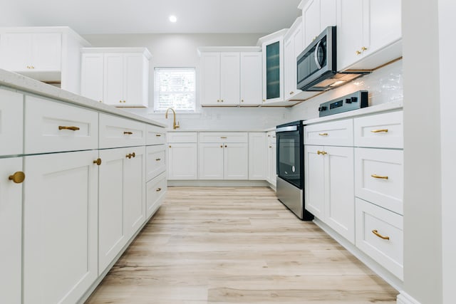 kitchen featuring glass insert cabinets, recessed lighting, light countertops, white cabinetry, and stainless steel appliances