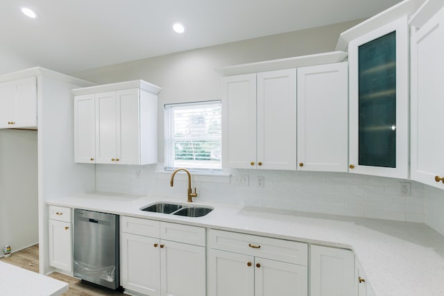 kitchen featuring stainless steel dishwasher, a sink, white cabinetry, and tasteful backsplash