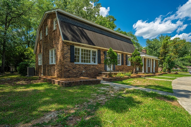 100 Colonial Dr, Goose Creek, SC 29445 - dutch colonial featuring a gambrel roof, brick siding, central air condition unit, a shingled roof, and a front lawn