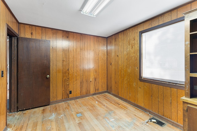 empty room with light wood-type flooring and wood walls