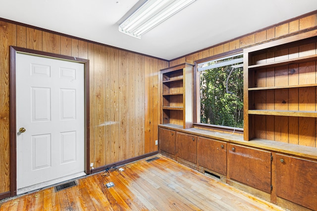 unfurnished office with light wood-type flooring and wooden walls