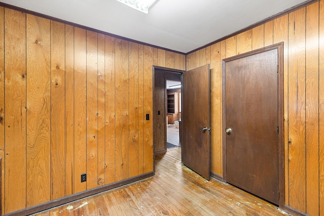 corridor featuring light wood-type flooring and wood walls