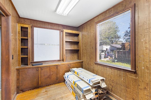 office area with ornamental molding, wooden walls, and light hardwood / wood-style floors