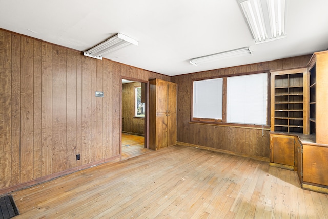 empty room with light hardwood / wood-style flooring and wooden walls