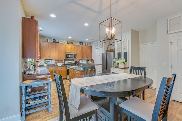 dining area with a chandelier, light wood-style floors, recessed lighting, and baseboards