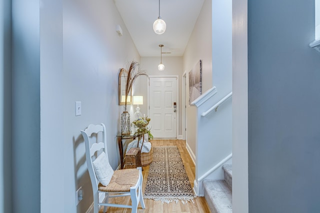 hallway featuring light wood-type flooring, baseboards, and stairway