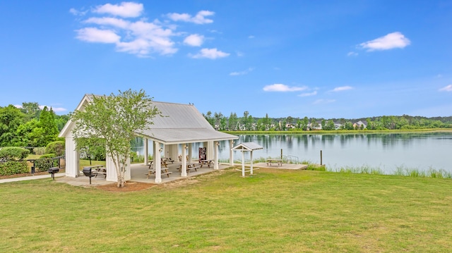 rear view of house with a yard, a water view, a patio, and metal roof