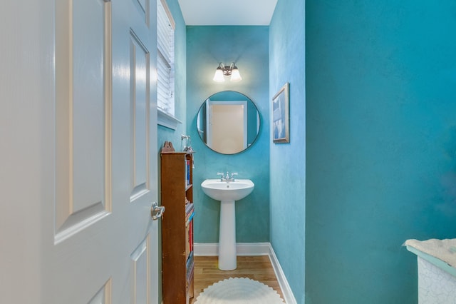 bathroom featuring wood finished floors, baseboards, and a sink