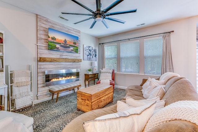 living room with baseboards, a ceiling fan, and a fireplace