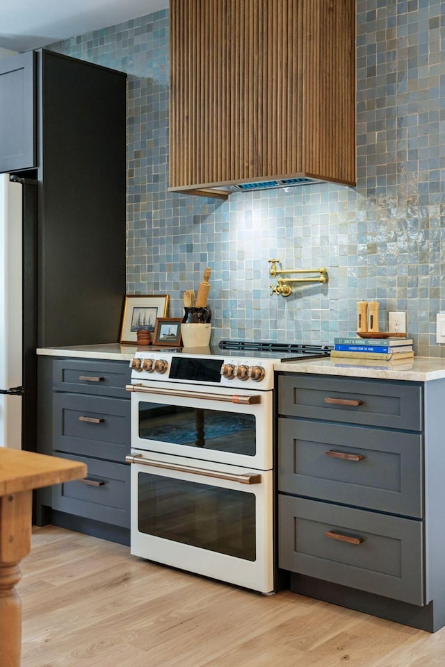 1012 E Erie Ave, Folly Beach, SC 29439 - kitchen featuring double oven range, gray cabinets, light countertops, wall chimney range hood, and decorative backsplash