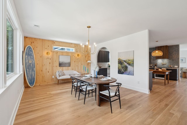 1012 E Erie Ave, Folly Beach, SC 29439 - dining room featuring light wood finished floors, baseboards, wooden walls, and a chandelier