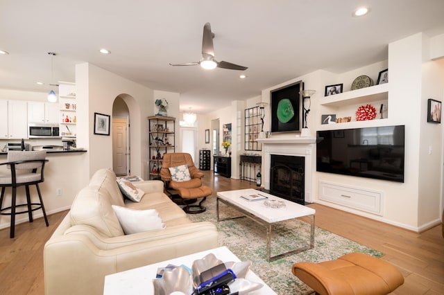 1231 Wild Olive Dr, Mount Pleasant, SC 29464 - living room featuring arched walkways, light wood finished floors, a ceiling fan, a fireplace, and recessed lighting