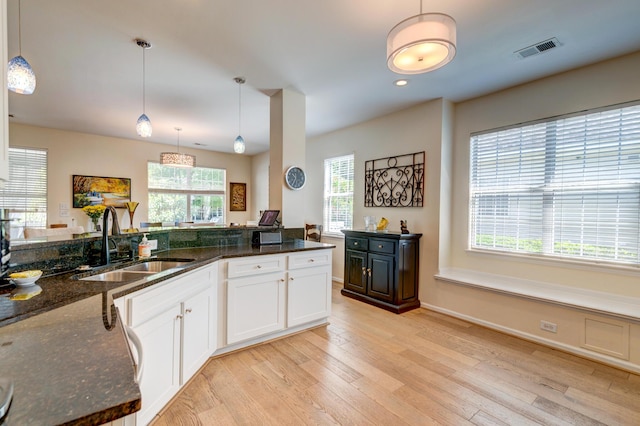 1231 Wild Olive Dr, Mount Pleasant, SC 29464 - kitchen with a sink, light wood-style floors, dark stone countertops, white cabinets, and pendant lighting
