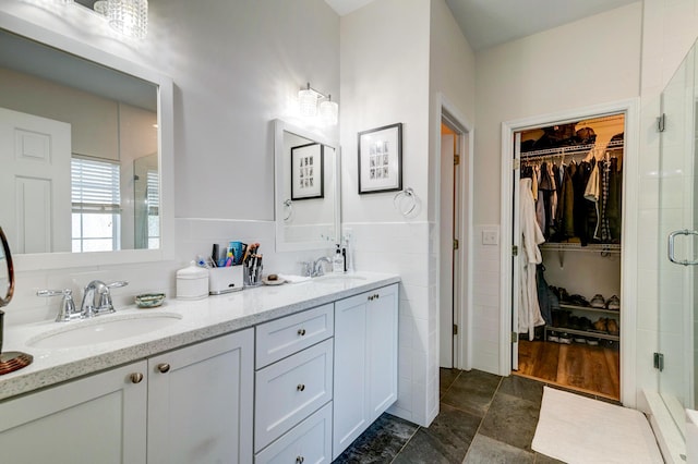 1231 Wild Olive Dr, Mount Pleasant, SC 29464 - bathroom featuring a walk in closet, a stall shower, double vanity, wainscoting, and tile walls