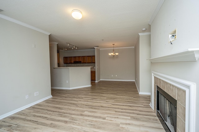 45 Scyamore Ave Unit 623, Charleston, SC 29407 - unfurnished living room featuring a tiled fireplace, light wood finished floors, a chandelier, a textured ceiling, and ornamental molding